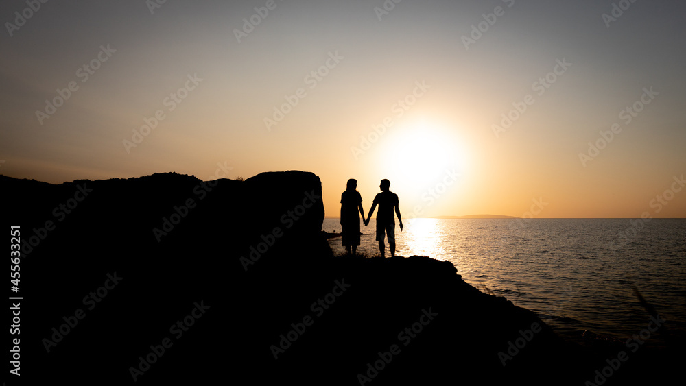 A couple of lovers holding hands at sunset by the sea