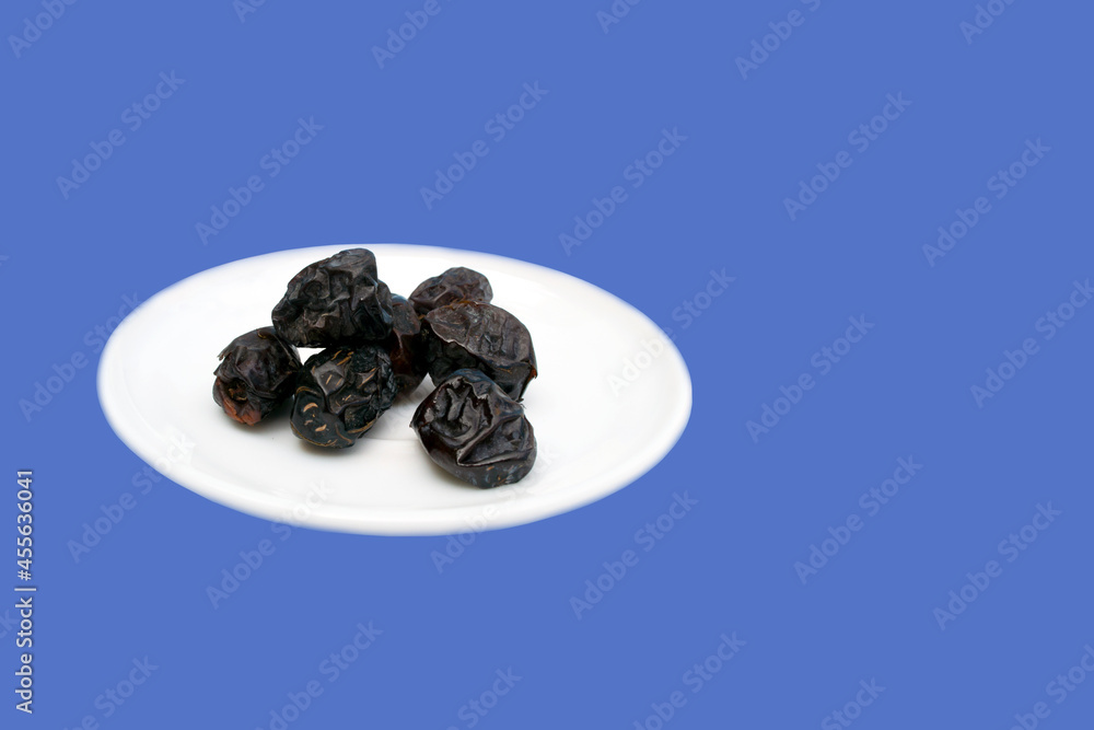 Dates with brown color are placed on a plate with a dark blue background
Dates with brown color are placed on a plate with a dark blue background