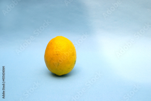 single lemon fruit on blue background and light shadow