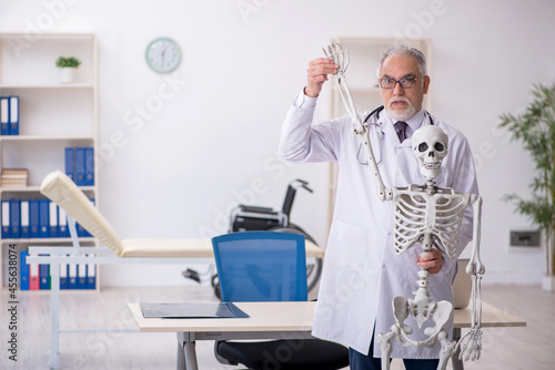 Old male doctor demonstrating human skeleton