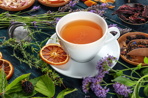 Tea. Herbs, flowers and fruit around a cup of tea, on a dark rustic wooden background