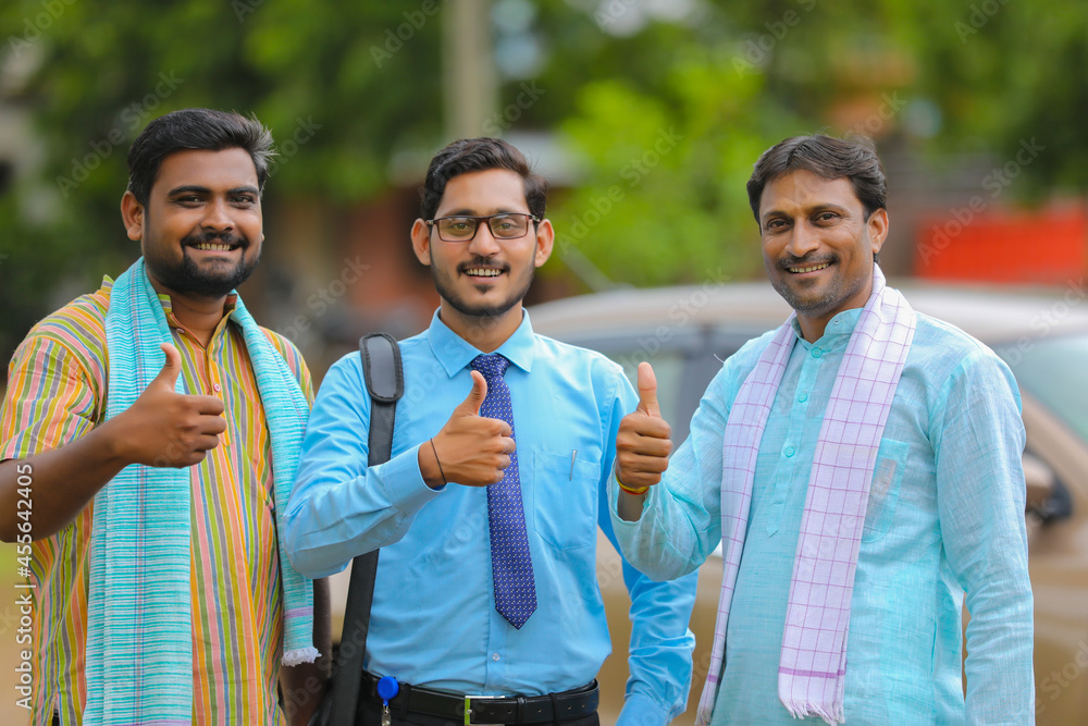 Vehicle loan concept: Young indian banker and farmers standing with new car and showing thumps up.