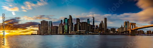 Lo straordinario skyline di New York City. Fiume con palazzi illuminati come sfondo. Foto Panoramica in lunga esposizione al tramonto © Matteo