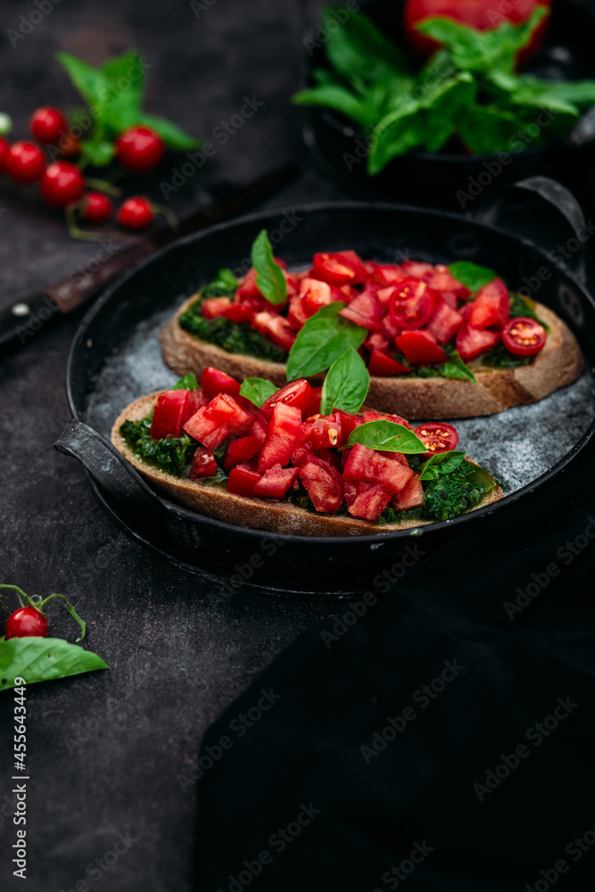 Bruschetta with pesto and tomatoes on a dark background Bruschetta with pesto and tomatoes on a dark background