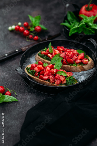Bruschetta with pesto and tomatoes on a dark background