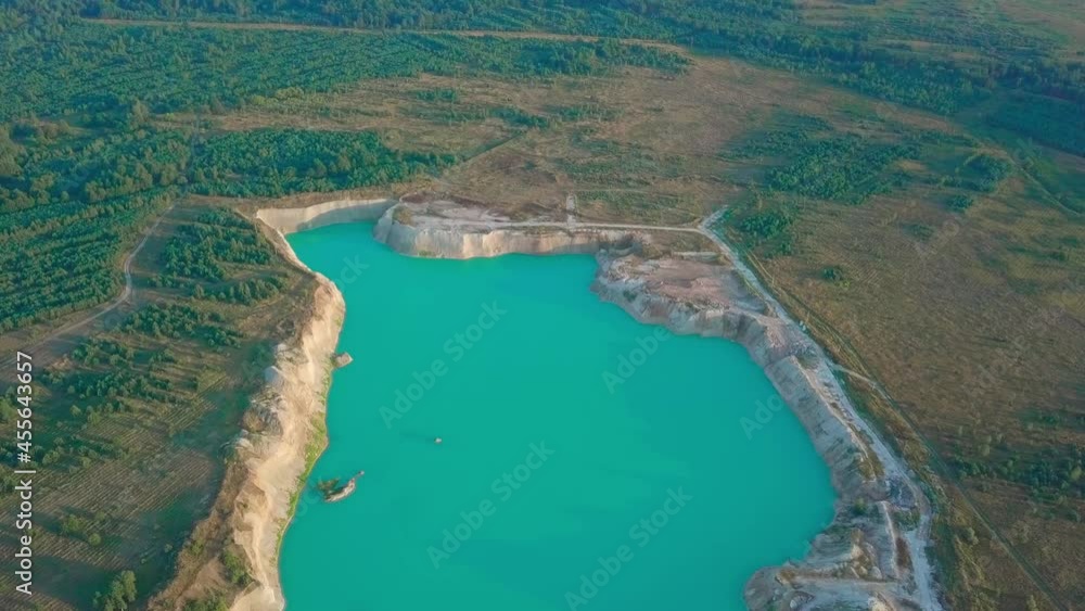 Artificial lake in a chalk quarry. Amazing industrial landscape. Drone view of opencast mine. Turquoise background of the water in open pit. Technogenic mountains formed during chalk mining. Artificial lake in a chalk quarry. Amazing industrial landscape. Drone view of opencast mine. Turquoise background of the water in open pit. Technogenic mountains formed during chalk mining.