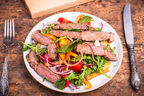 Vegetable salad with pieces of beef steak in a plate on the table - healthy food, rustic style
