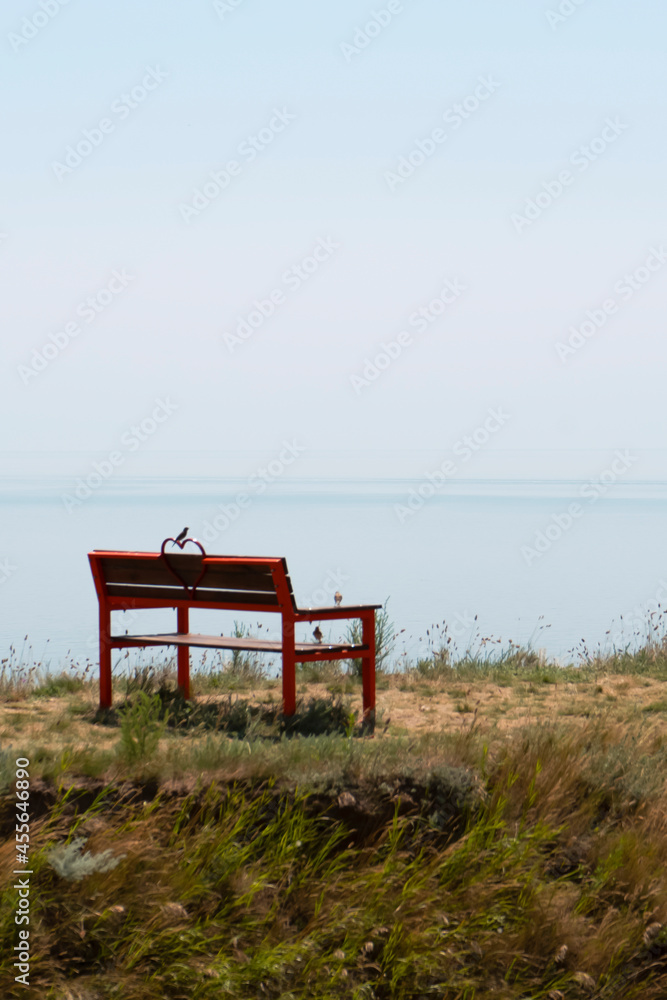 Red bench on the sea coast cliff
