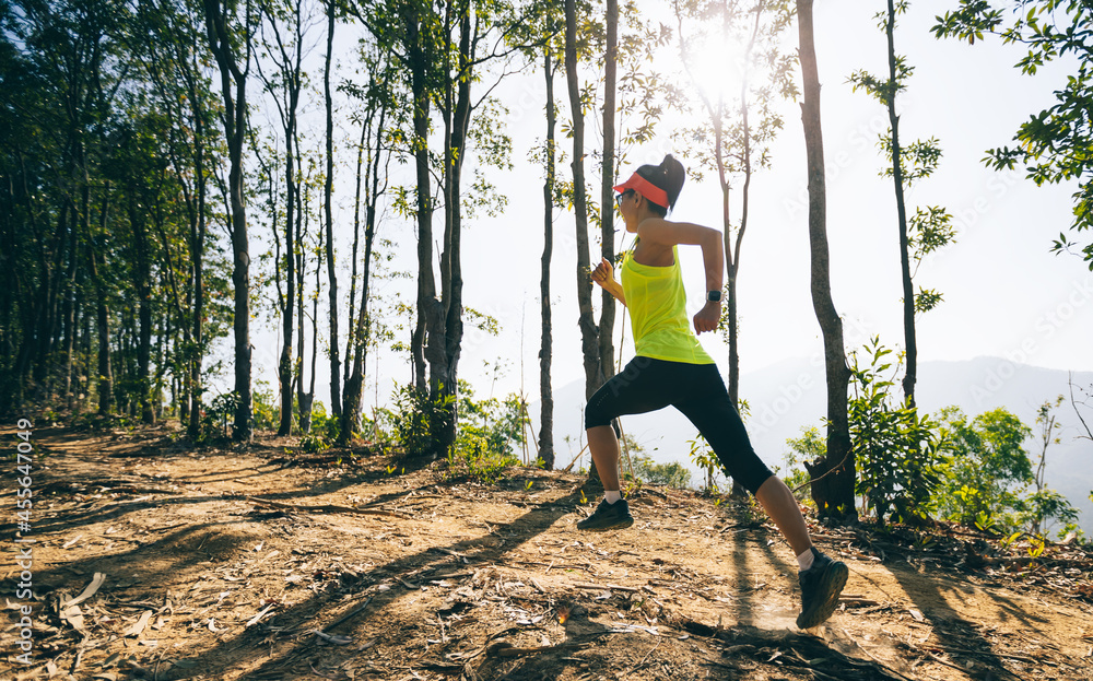 Fitness woman trail runner running on sunrise tropical forest mountain peak