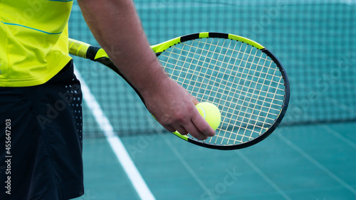 Close-up of tennis racket and yellow ball. Tennis sport. Men holds a tennis racket. Sports background. Copy space.