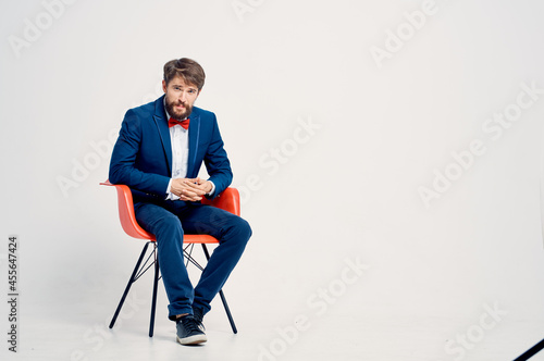bearded man in suit sitting on red chair posing Professional