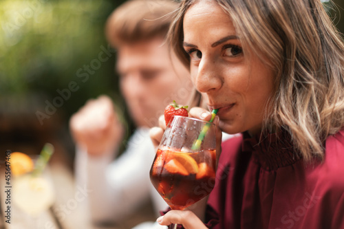 side portrait of happy young woman drinking a refreshing cocktail outdoors