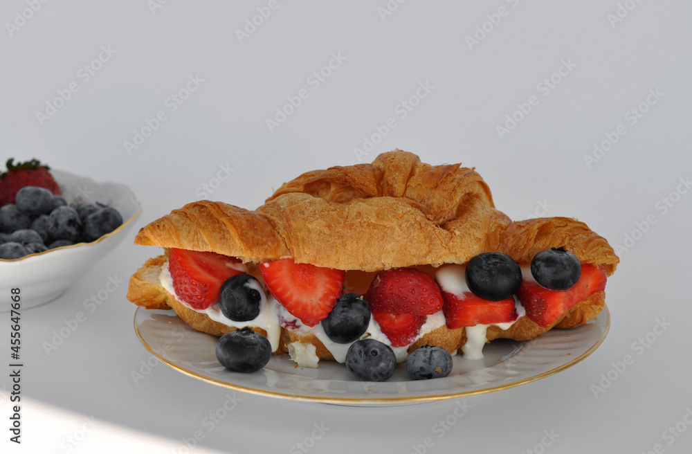 fresh croissant with cream, strawberries and blueberries