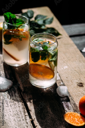 Cold cocktail with tangerine and mint on a wooden table