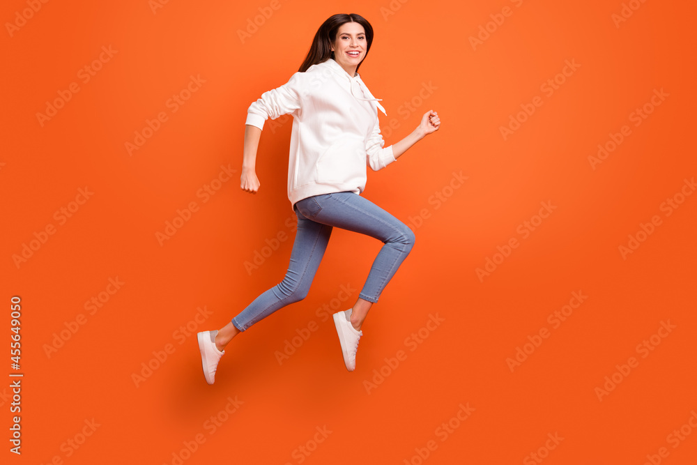Full length body size profile side view of lovely carefree cheerful girl jumping running isolated bright orange color background