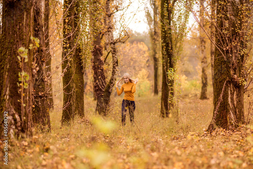 girl walks in the autumn forest. A young woman is spinning against the background of orange trees.