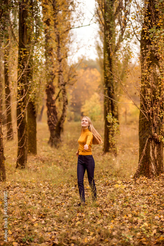 girl walks in the autumn forest. A young woman is spinning against the background of orange trees.