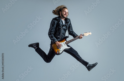 Valokuva emotional bearded rock musician playing electric guitar in leather jacket and ju
