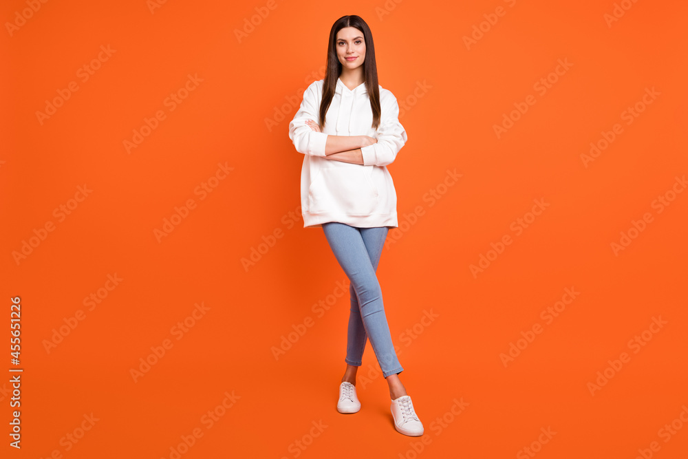 Full length body size view of attractive cheery girl folded arms making step isolated over bright orange color background Full length body size view of attractive cheery girl folded arms making step isolated over bright orange color background