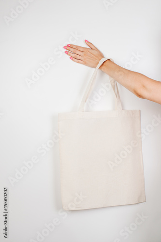 Female hand holding eco-bag. Mocap of reusable cotton eco-bag on white insulated background, concept of zero waste. 