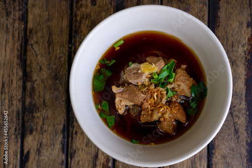 Braised pork noodles in a white bowl on a wooden table