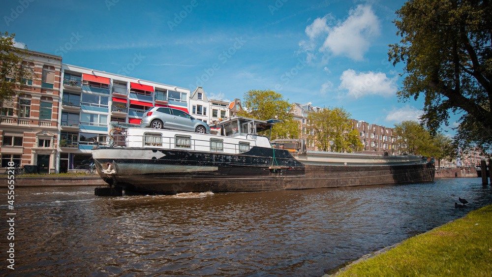 View of a ship passing elevating road bridge in amsterdam canal. Ship under open bridge over the canal. View of a ship passing elevating road bridge in amsterdam canal. Ship under open bridge over the canal.