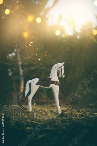 Magical image of vintage rocking horse in the forest at sunset