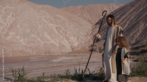 Jesus walks with the girl holding her hand towards the reservoir. High quality 4k footage