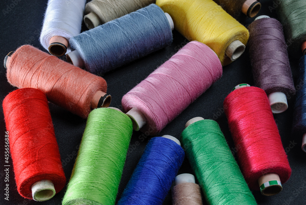 colorful spools of thread on black background colorful spools of thread on black background