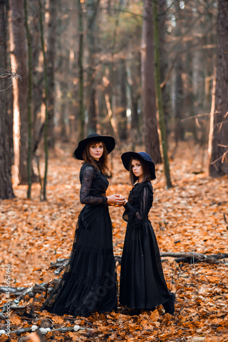 Two witches in the autumn forest. Mother and daughter brew a potion.