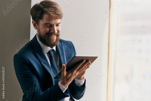 Cheerful business man near the window with a tablet in his hands communication