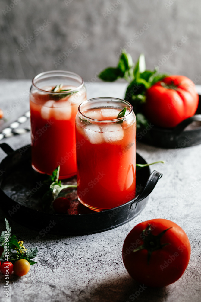 Tomato juice with ice in a glass on a gray background Tomato juice with ice in a glass on a gray background