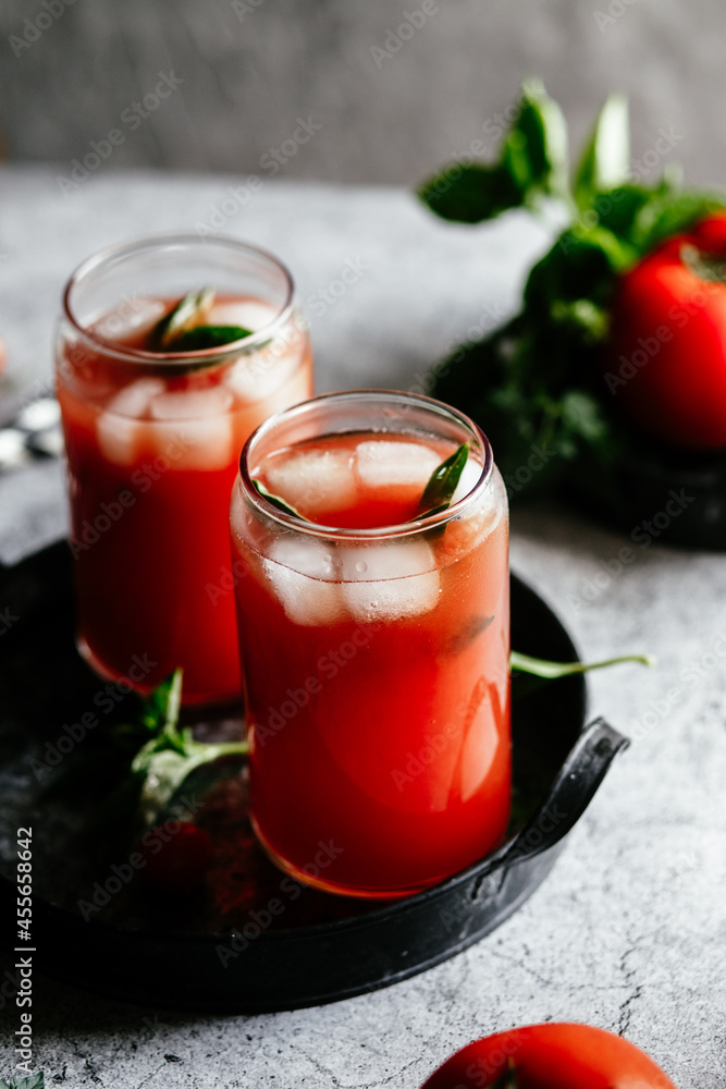 Tomato juice with ice in a glass on a gray background Tomato juice with ice in a glass on a gray background