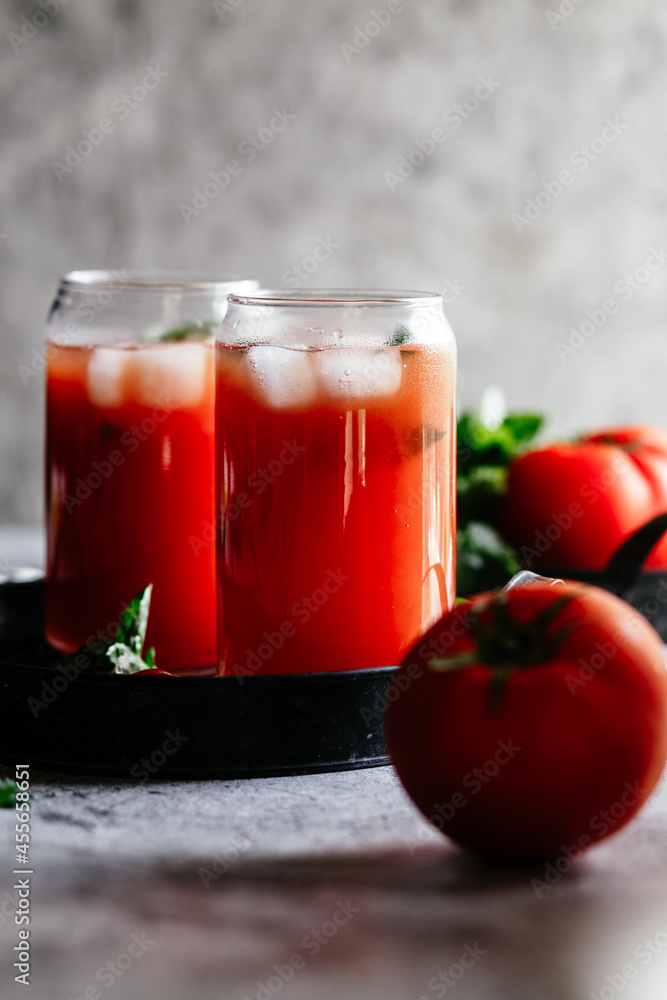 Tomato juice with ice in a glass on a gray background Tomato juice with ice in a glass on a gray background