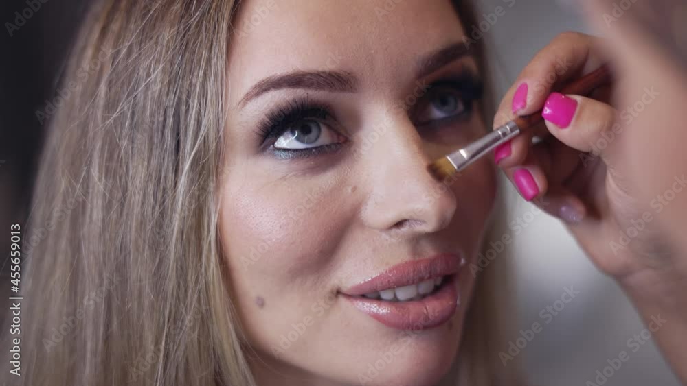 Makeup artist contouring model's nose using a brush Makeup artist contouring model's nose using a brush