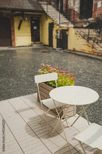 stylish cafe with decor of green living plants  white table and chairs without visitors. eco-friendly direction in public catering and restaurants. landscaping of restaurants  selective focus