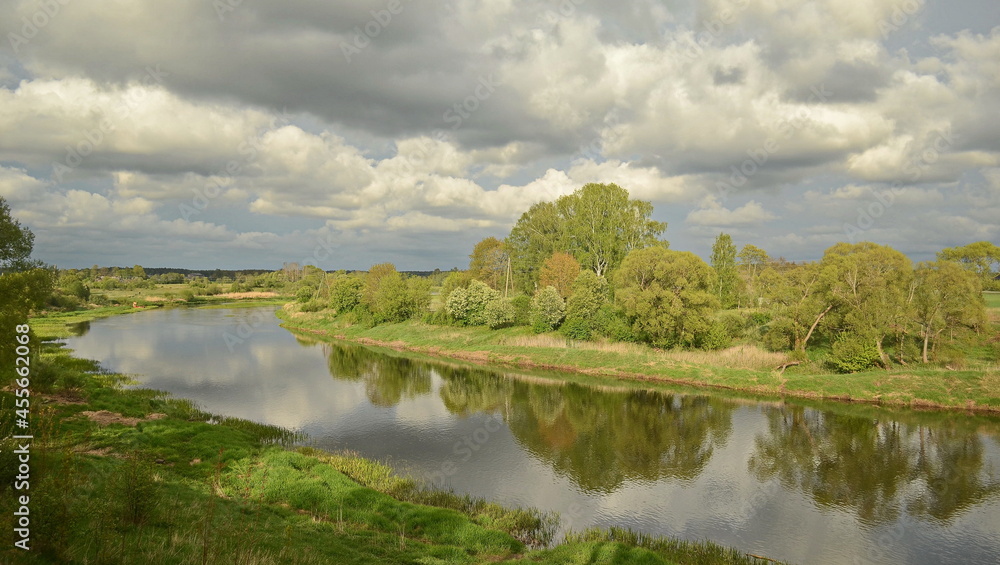 Landscape with river Venta, trees, clouds and reflection in sunny spring day, Skrunda, Latvia.