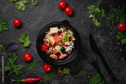 Delicious salad with chicken, olives and fresh herbs, a fresh salad on the menu of a fast food restaurant on a dark stone table. Healthy option of fast food..