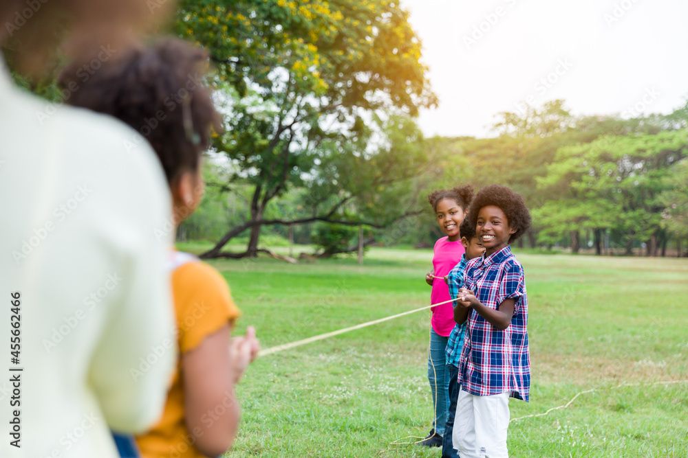 Group of African American boy and girl playing tug of war together in the park. Cheerful children with curly hair having fun with tug of war. Black children people playing tug of war Group of African American boy and girl playing tug of war together in the park. Cheerful children with curly hair having fun with tug of war. Black children people playing tug of war