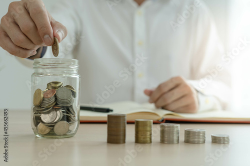 Businessman holding a coin in a piggy bank. Money saving , financial accounting, income and investment concept.