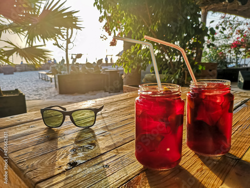 Cold drinks on a wooden table. Non alcoholic coctails in unidentified local bar in Cape Verde, Africa. Selective focus on colorful glasses, blurred background.