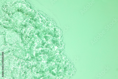 Green transparent clear water surface texture with ripples, splashes and bubbles. Abstract summer nature background. Copy space for cosmetics.