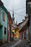 Wąska kamienna uliczka z kolorowymi budynkami i kościołem