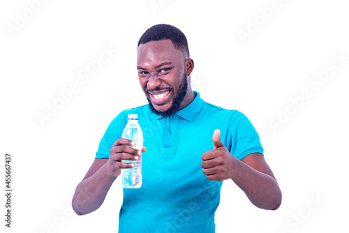 young man holding a bottle of mineral water and showing his thumb while smiling.