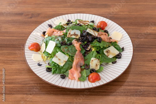 Great spinach salad with smoked salmon, Parmesan cheese slices, sliced black olives and olive oil