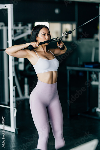 Young beautiful muscular fit woman exercising building muscles at gym