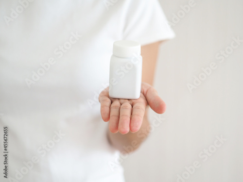 Concept of preventing viral disease or covid-19. Woman's hand holding a bottle with vitamins, tablets, paniculata. closeup photo, blurred.