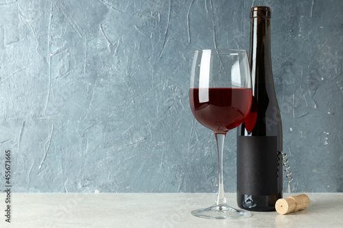 Bottle and glass of red wine, and corkscrew against blue textured background