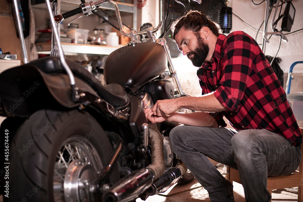 Junger Mechaniker repariert Motorrad, Biker, Werkstatt, Lange Haare, Bartträger