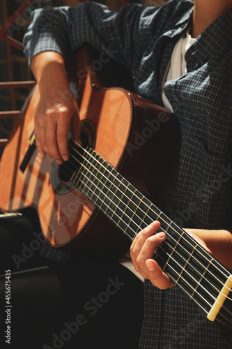 Woman in shirt playing on classical guitar